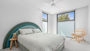 A modern bedroom with a bed, a chair, and large windows. - Gorgeous George Barwon Heads (Barwon Heads)