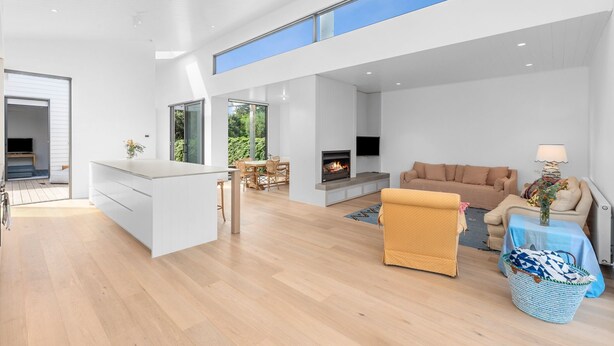 A modern open-plan living area with a kitchen, dining space, and a fireplace. - Gorgeous George Barwon Heads (Barwon Heads)