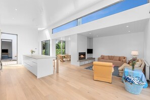 A modern open-plan living area with a kitchen, dining space, and a fireplace. - Gorgeous George Barwon Heads (Barwon Heads)