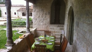 An outdoor dining area with stone walls, a table set for four, and a view of a courtyard. - Gite DE Bellecombe AU Chateau Plaisir de la Campagne Proche des Parcs de Loisirs (Puymirol)