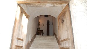A staircase leading to a room with a wooden door and a small table. - Gite DE Bellecombe AU Chateau Plaisir de la Campagne Proche des Parcs de Loisirs (Puymirol)