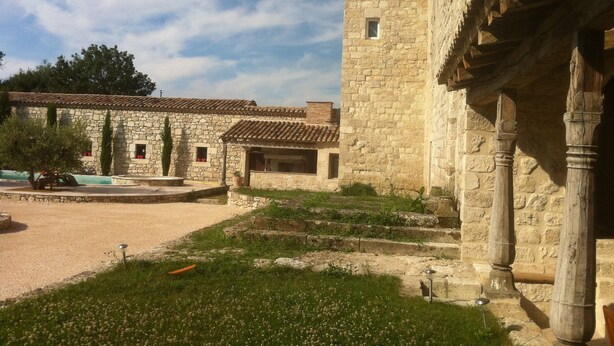 A stone building with a tiled roof, a courtyard with a gravel path, and a small garden area. - Gite DE Bellecombe AU Chateau Plaisir de la Campagne Proche des Parcs de Loisirs (Puymirol)