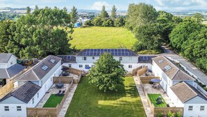 Un ensemble résidentiel composé de plusieurs maisons blanches, dotées de panneaux solaires sur les toits, et agrémenté d’une pelouse centrale.