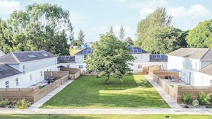 Un ensemble résidentiel comprenant plusieurs maisons, une pelouse centrale et des panneaux solaires sur les toits.