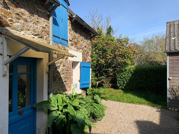 A rustic stone building with a gravel path leading to a blue door. - Charmante Maison Familiale (Binic-Étables-sur-Mer)