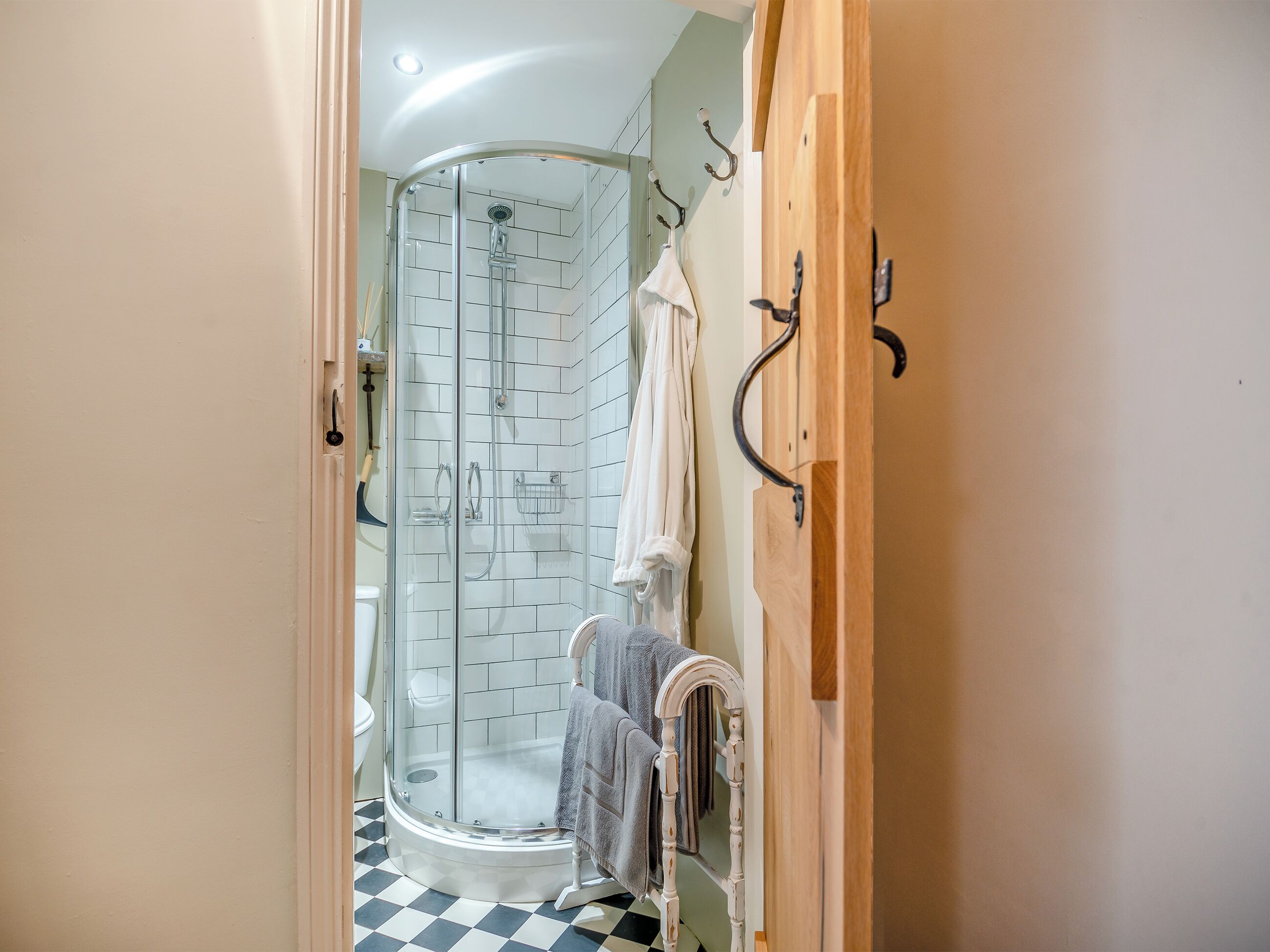 Ein Badezimmer mit einer Duschkabine, einem weißen Heizkörper und einem Schachbrettboden.