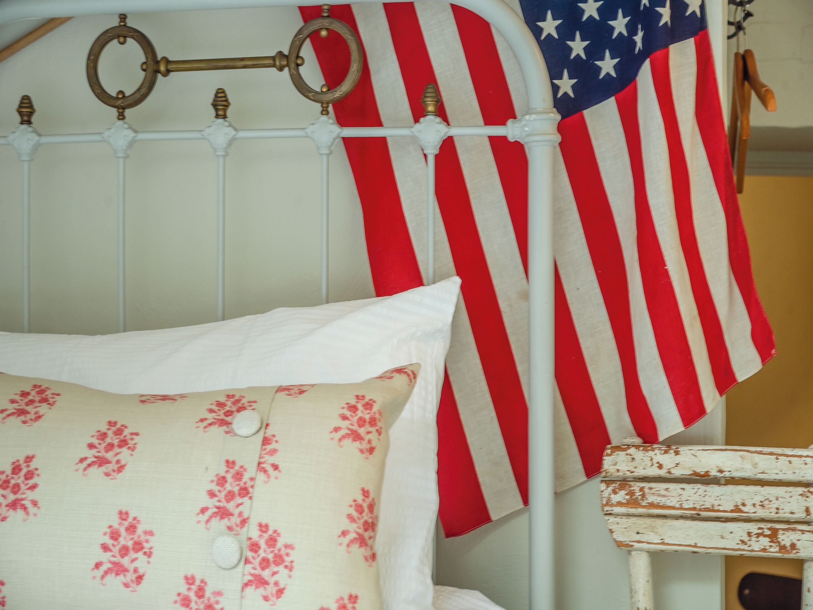 A bed with white bedding and a pillow with a floral pattern.