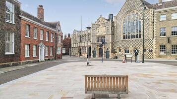 A spacious public square with a wooden bench in the center, surrounded by historic buildings with varied architectural styles.