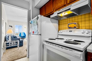Cozy living space with a fully equipped kitchen featuring a stove, refrigerator, and wooden cabinets.