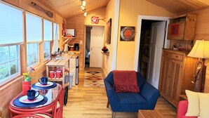 Un interior de cabaña acogedor, con comedor, sala de estar con un sofá azul y cocina con armarios de madera.