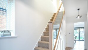 A staircase with carpeted steps and wooden handrails, leading to a room with a large window and a view of the outdoors. - 5 bedroom accommodation in Ashbourne (Ashbourne)