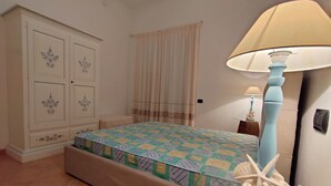 Un dormitorio con una cama, una mesita de noche, una lámpara, una estrella de mar decorativa y un armario.