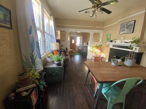 Enjoy meals in this inviting dining area with a fireplace, potted plants, and a wooden table.