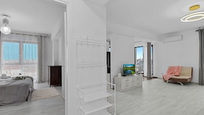 Una habitación de hotel moderna con una cama, un televisor, un sofá y un estante blanco.