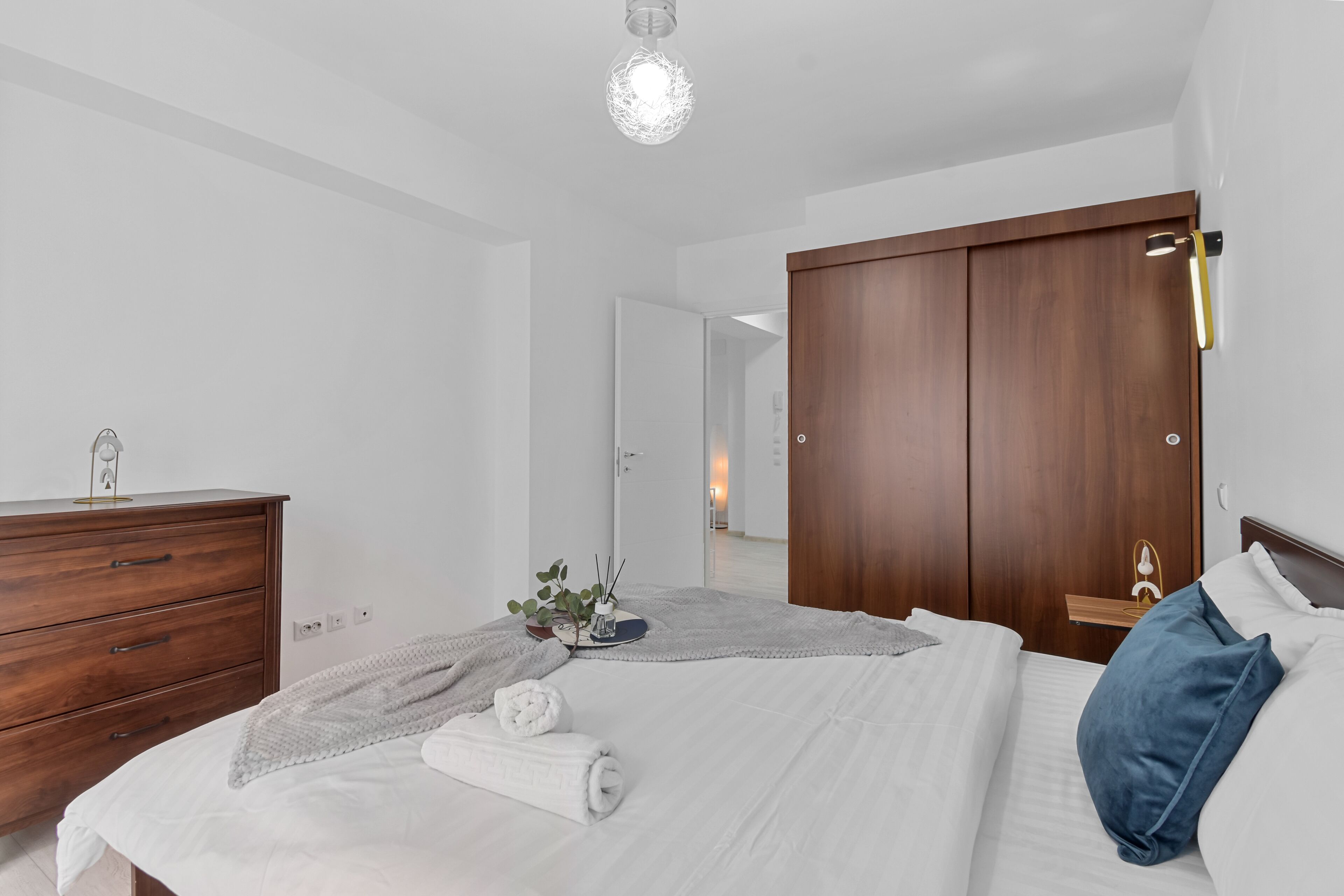 Ein modernes Schlafzimmer mit einem großen Bett, einem Holzschrank und einem Spiegel.