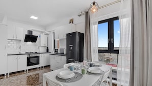 Una cocina moderna con armarios blancos, un refrigerador negro y un comedor con mesa dispuesta para cuatro.