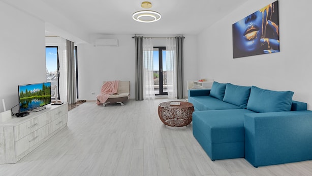 Una sala de estar moderna con un sofá azul, un televisor y una mesita de centro.