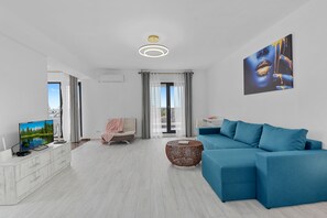 Uma sala de estar moderna com um sofá azul, uma televisão e uma mesa de centro.