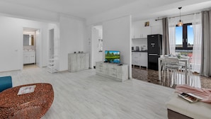 Una sala de estar moderna con televisión, comedor y cocina.