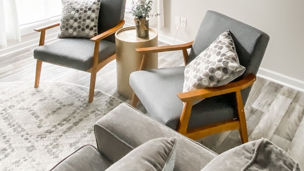 A living room with two armchairs, a coffee table, and a painting of a beach scene.