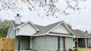 A single-story house with a gabled roof, a front porch, and a brick facade.