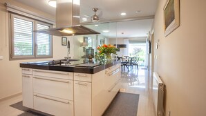 A modern kitchen with white cabinetry, a black countertop, and a central island.