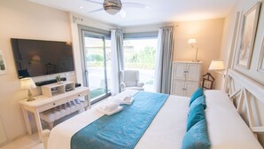 A hotel room with a large bed, a desk with a TV, a chair, and a view of the outdoors.