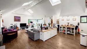 Een ruime woonkamer met een bank, een eettafel en een keukenhoek.