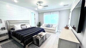 A modern bedroom with a bed, bedside table, nightstand, and a large mirror.