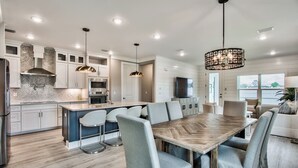 A modern kitchen with a central island, bar stools, and pendant lighting.