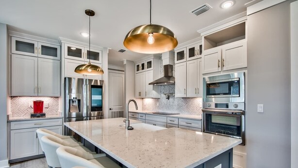 A modern kitchen with a central island, stainless steel appliances, and pendant lighting.
