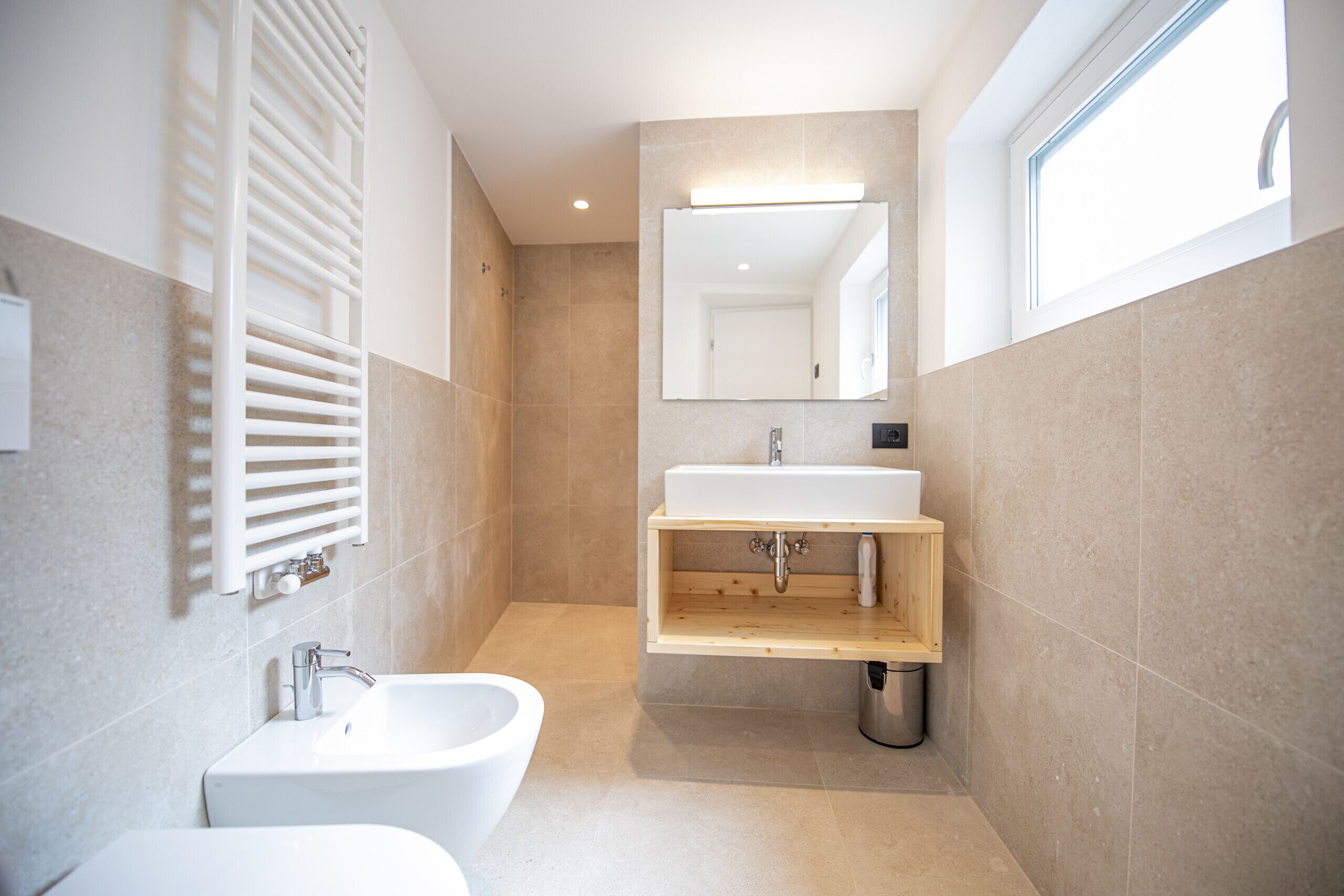 Une salle de bain moderne avec un lavabo blanc, un bidet et un meuble-lavabo en bois.