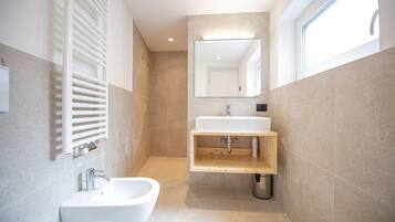 Une salle de bain moderne avec un lavabo blanc, un bidet et un meuble-lavabo en bois.