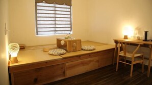 A cozy room with a low wooden bed, a small desk, and a chair.