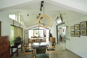 A dining area with a table and chairs, a hanging light fixture, and framed pictures on the wall.