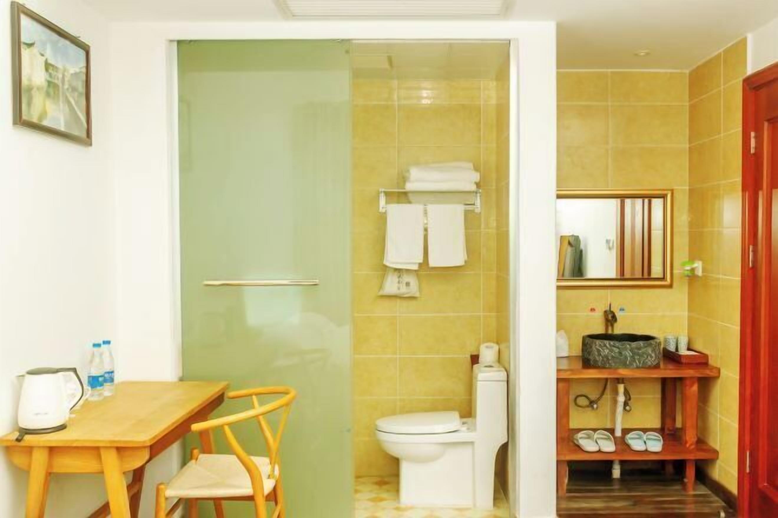 Un baño con ducha, inodoro, lavabo y una pequeña mesa con sillas.