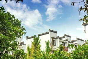 A traditional building with multiple white walls and tiled roofs, surrounded by lush greenery.
