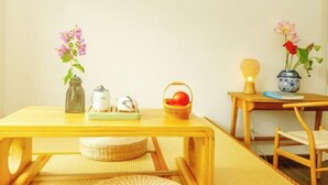 A wooden table with a woven mat, a small basket, and a vase with flowers.