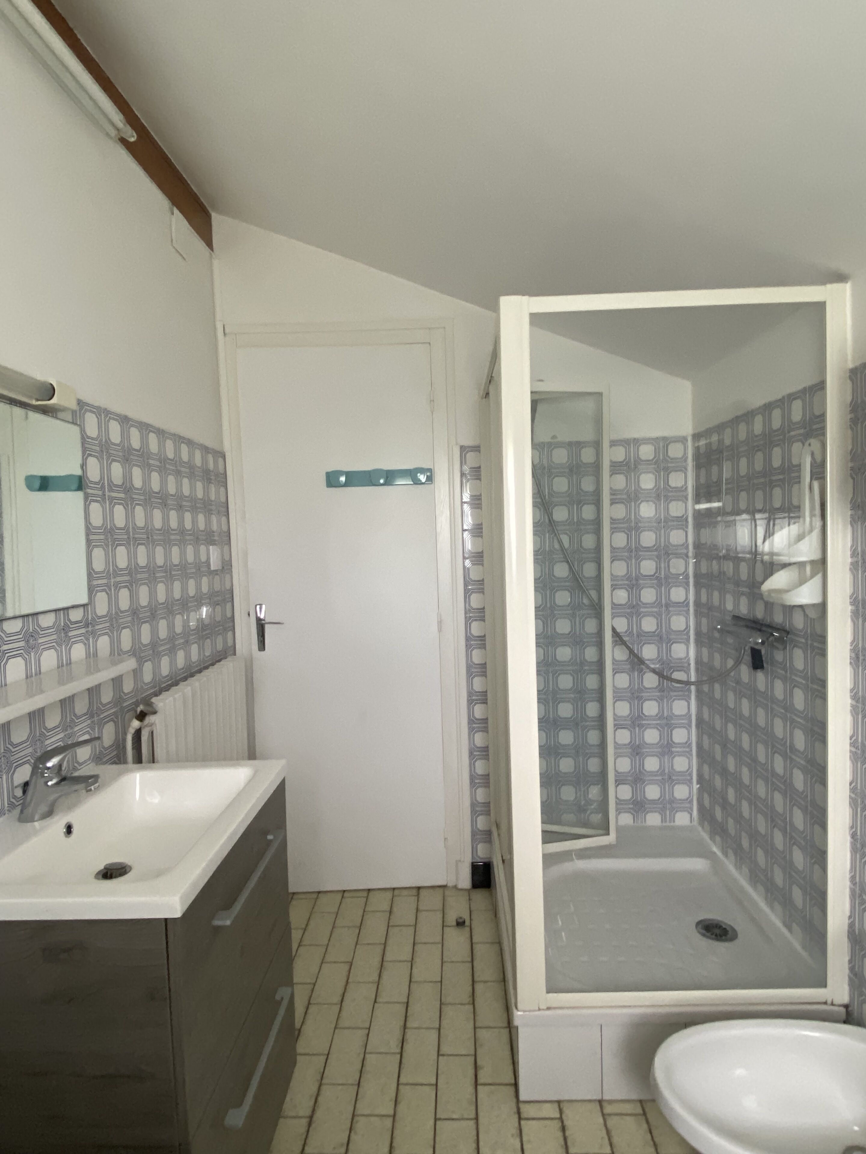 Un baño con tocador doble, cabina de ducha y paredes con azulejos estampados.