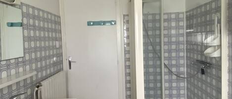 Un baño con tocador doble, cabina de ducha y paredes con azulejos estampados.