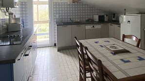 Una cocina con mesa, sillas, un refrigerador y una ventana.