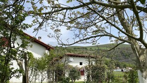 Un edificio blanco con techo rojo, rodeado de un campo verde y árboles.