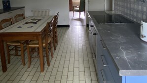 Una cocina con salpicadero de azulejos, una mesa de comedor de madera y sillas.