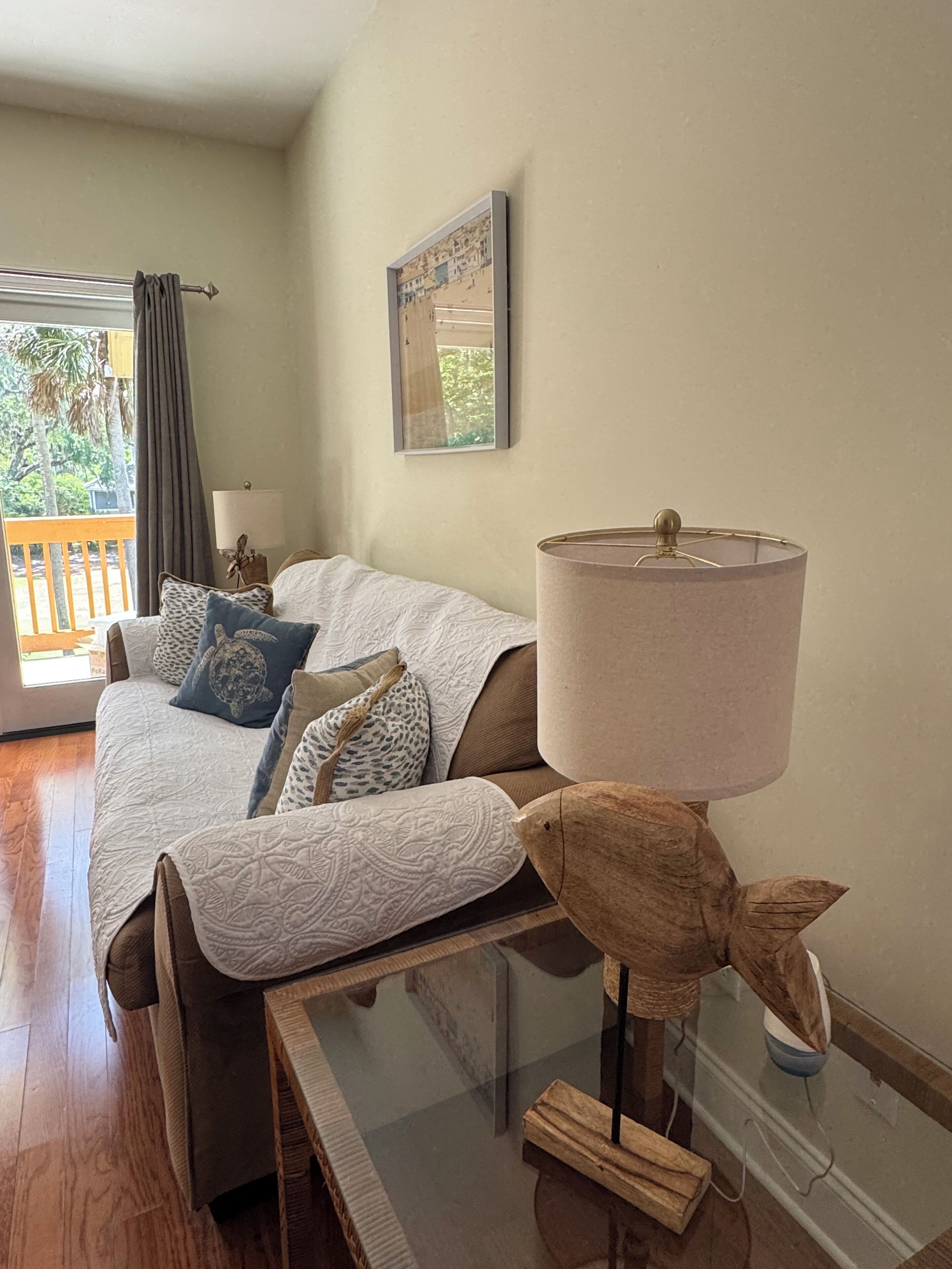 Un dormitorio con una cama, una lámpara con forma de pez de madera, un cuadro en la pared y vistas al exterior.