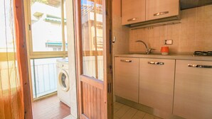 A compact kitchen with a built-in washing machine, a sink, and cabinets.