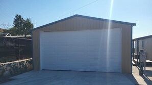 A single-story building with a garage door, a stone wall, and a metal fence. - Lake Roosevelt View Retreat Grand Coulee (Grand Coulee)