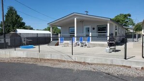 A single-story building with a fenced patio area, a covered outdoor seating area, and a small pool. - Lake Roosevelt View Retreat Grand Coulee (Grand Coulee)