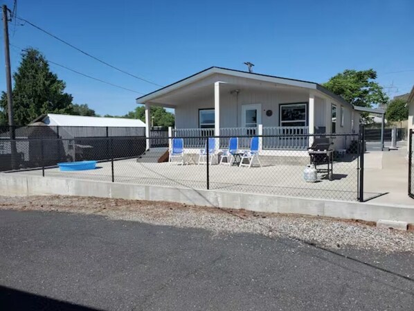 A single-story building with a fenced patio area, a covered outdoor seating area, and a small pool.