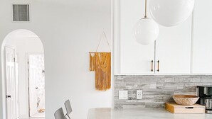 Una cocina moderna con una isla grande, luces colgantes y un salpicadero de piedra.