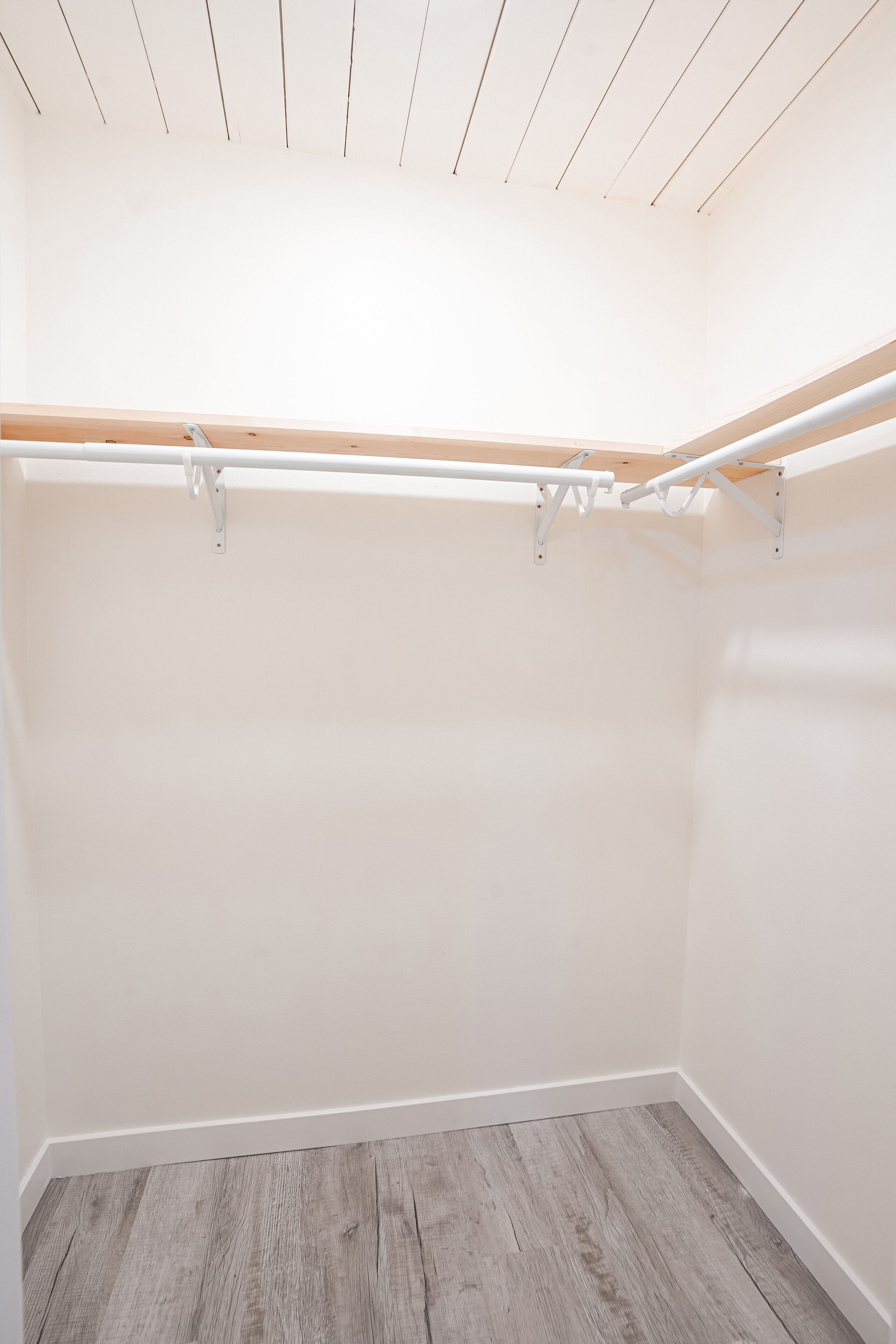 Een kamer met houten vloer, witte muren en een plafond met houten balken.